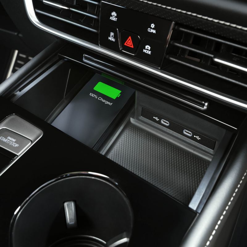 A close-up view of a VW Atlas 2025 centre console with a wireless charging pad indicating a green charging status.