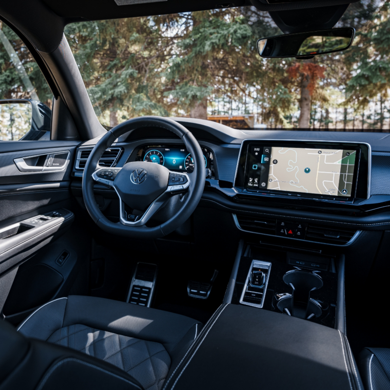 L'intérieur de l'Atlas Cross Sport 2025 montre le siège conducteur avec un volant, un tableau de bord numérique et un écran tactile central.