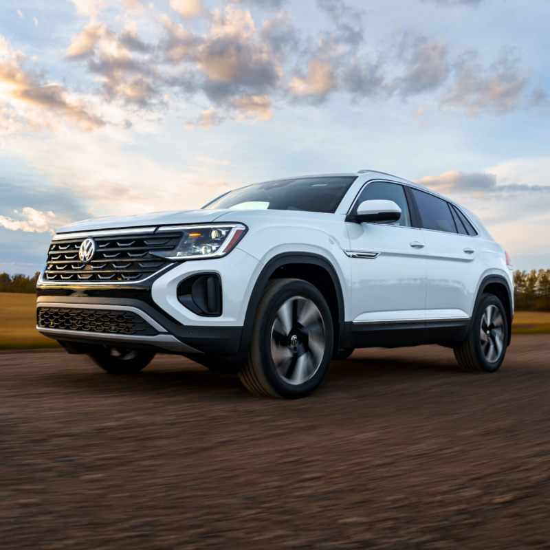 Un Atlas Cross Sport 2025 blanc fonce sur une route, l'arrière-plan étant flou pour accentuer son mouvement.