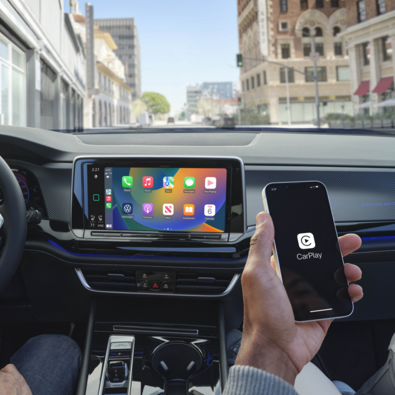 La main d'un passager tient un smartphone affichant "Android Auto", connecté au système d'infodivertissement du Cross Sport 2025, présentant une variété d'icônes d'applications sur l'écran tactile.