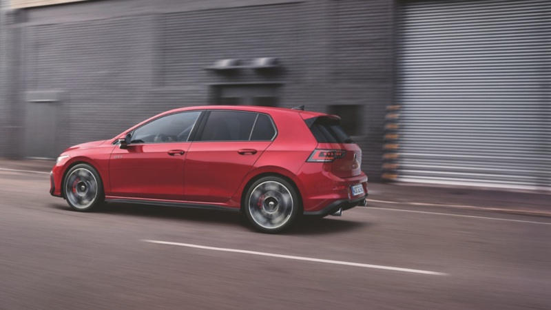 Une Volkswagen Golf GTI rouge en mouvement, mettant en valeur ses doubles sorties d'échappement chromées.