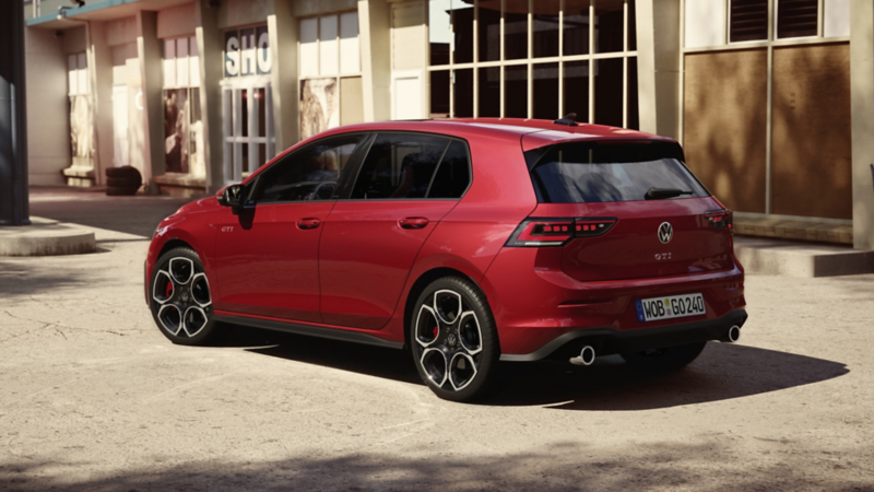 Volkswagen Golf GTI rouge garée devant un bâtiment.