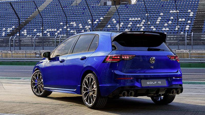 Vue arrière d'une Volkswagen Golf R bleue garée dans une zone de stands d'un circuit de course.