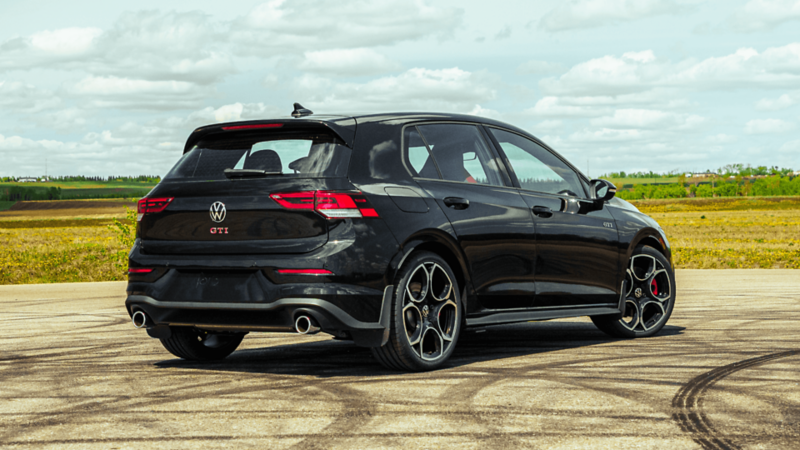 Vue arrière trois quarts d’une VW Golf GTI noire mettant en valeur son design aérodynamique.