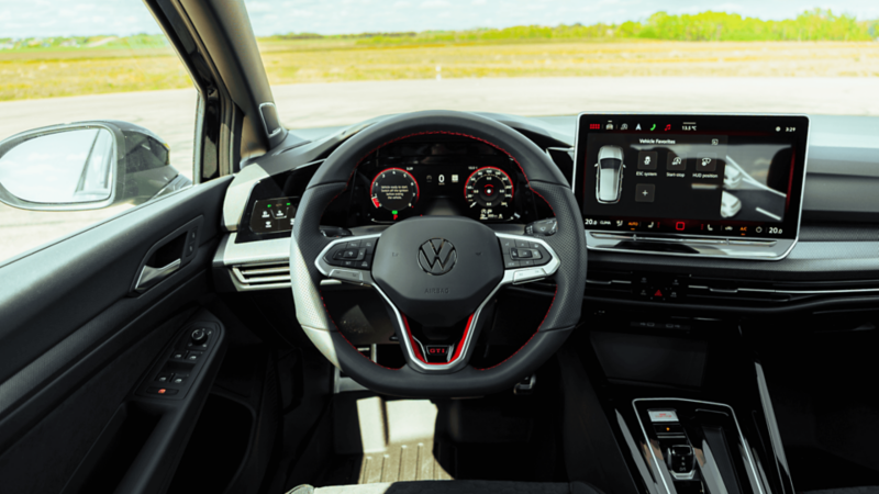 Poste de conduite de la Volkswagen Golf GTI 2026 avec volant, tableau de bord numérique et écran tactile central.