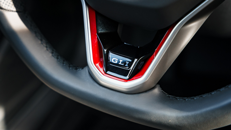 Close-up of GLI badge with red accent on the sport steering wheel. 