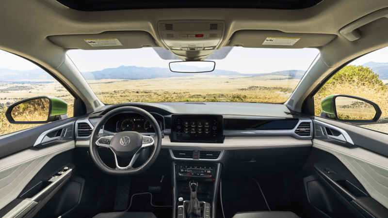 Interior view of the 2026 Volkswagen Taos, showing the dashboard, steering wheel, touchscreen display, and panoramic windshield.