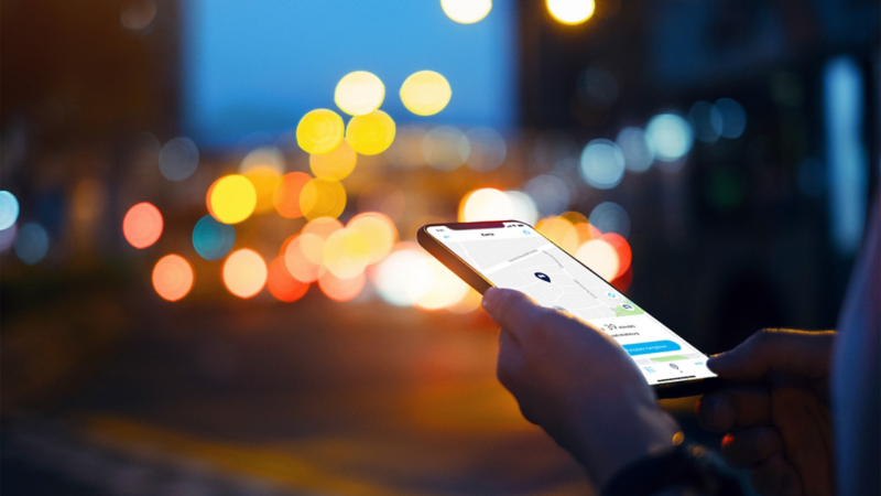 Photo showing a hand holding a smart phone with a VW app on the screen. 