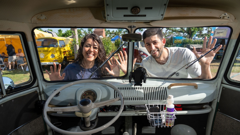 Dos jóvenes apoyados en el parabrisas de una VW T1.