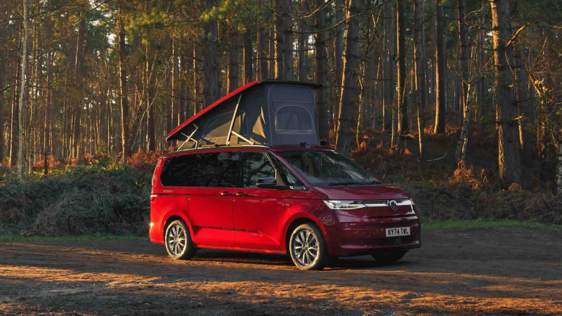 Photo showing a VW camper van parked against a woodland background with the roof module deployed.