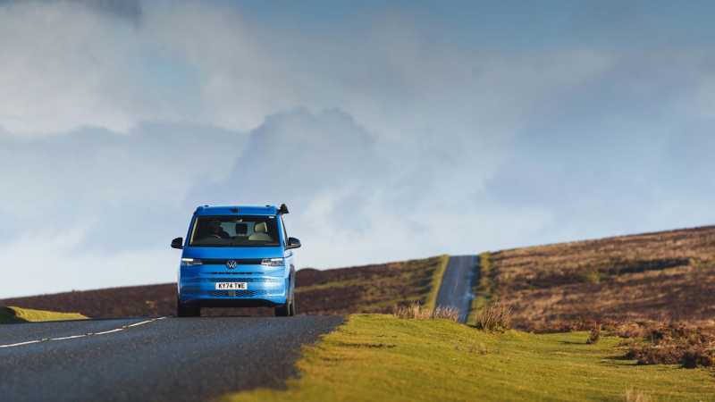 a blue California driving down a countryside road