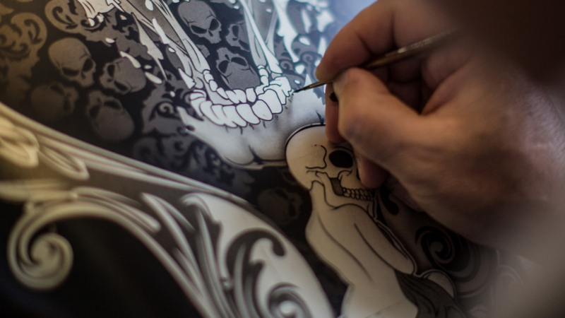 Andre Marty zeichnet mit dem Luftpinsel die Details an einem Motiv.