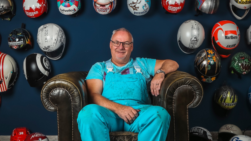 Andre Marty sitzt auf einem Stuhl vor seiner Helmsammlung.