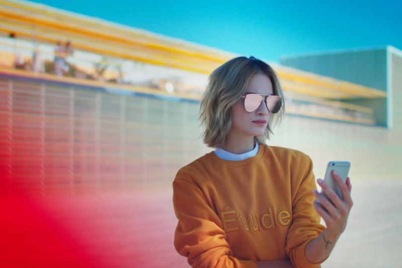 En kvinde med solbriller kigger i en telefon