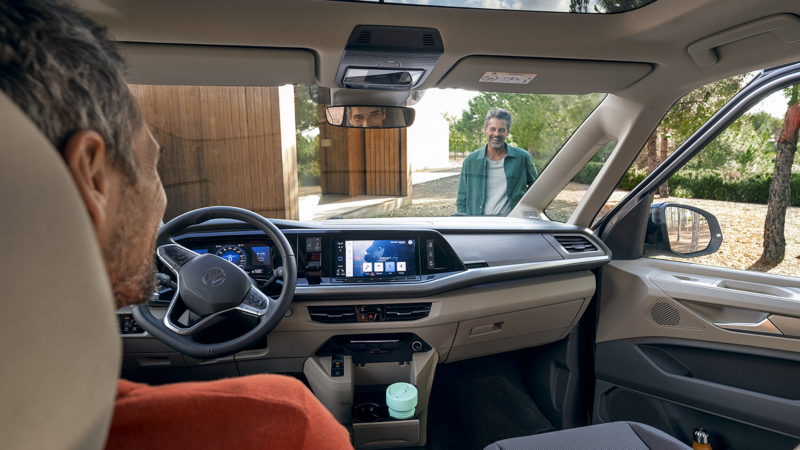 Un hombre en el interior de un vehículo VW esperando a que otro hombre suba al vehículo..
