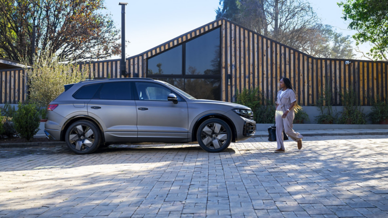 Happy family with dog in front of open luggage compartment of VW Touareg