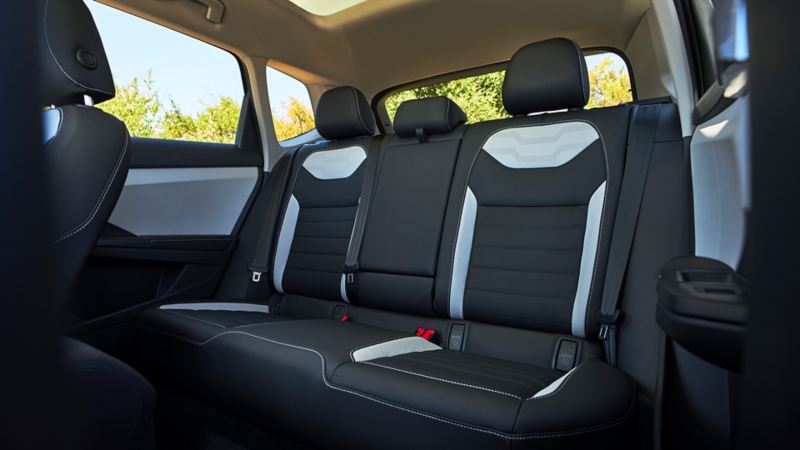 The interior of the 2025 Taos, view of the dashboard, steering wheel and infotainment system, from the rear seats.