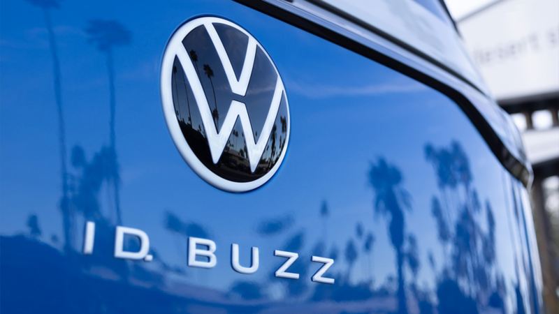 A man is sitting in the driver's seat of the Volkswagen ID. Buzz 2025, looking out at the ocean.