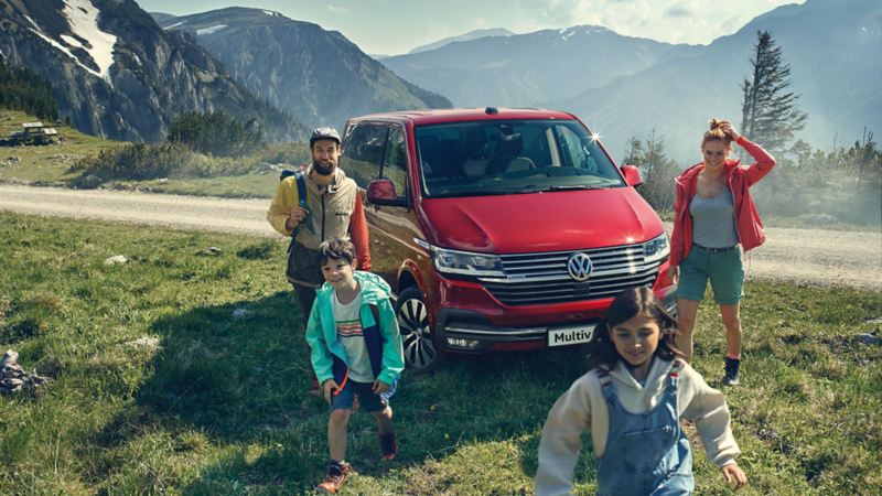 Volkswagen Multivan rosso dietro ad una famiglia con due bambini