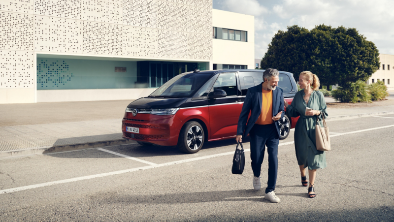 Una pareja paseando delante del VW Multivan. 