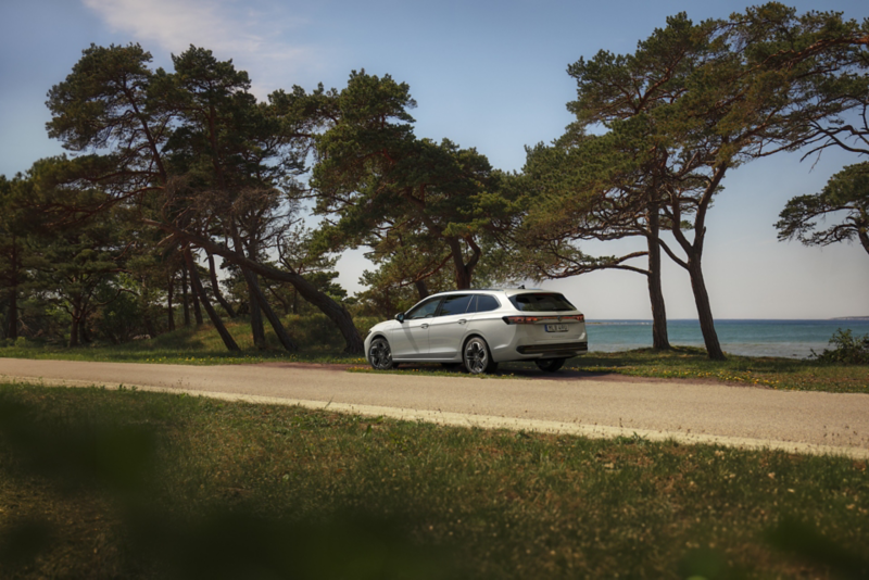 VW Passat parkerad vid en strand fotad snett bakifrån.