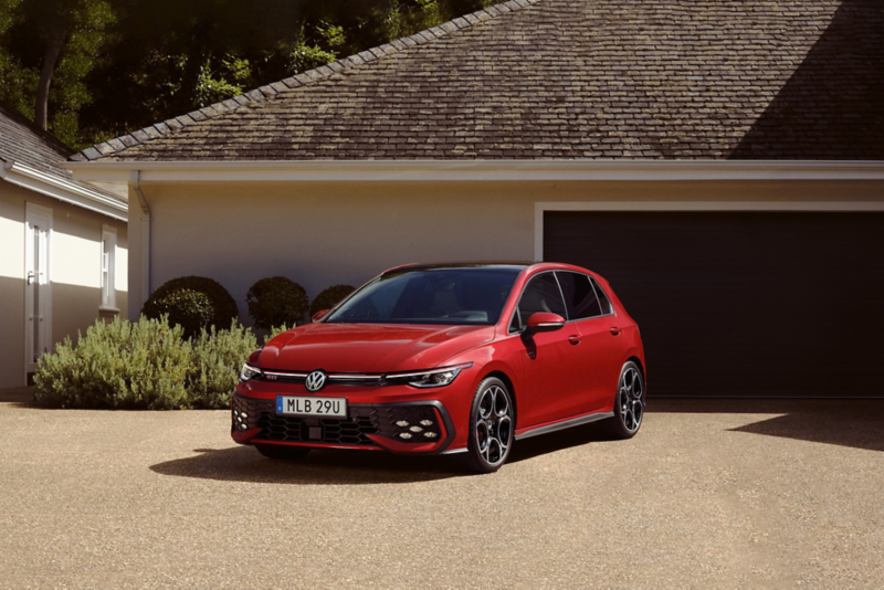 En röd Golf GTI parkerad på en uppfart utanför en villa