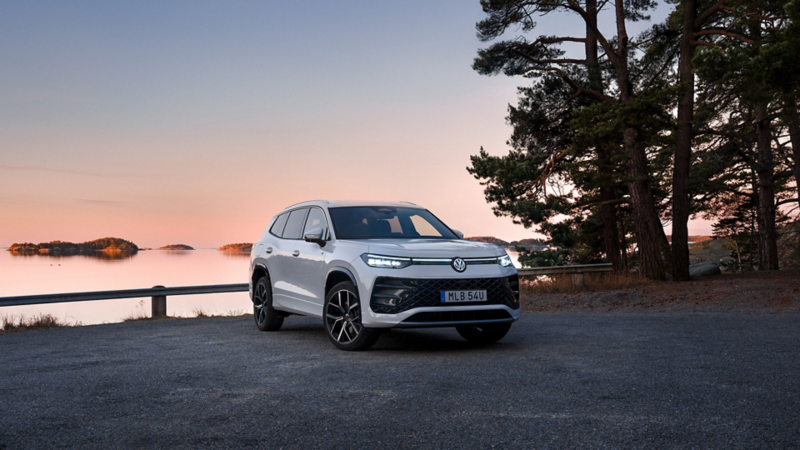 En vit VW Tayron står parkerad vid havet i skymmningen