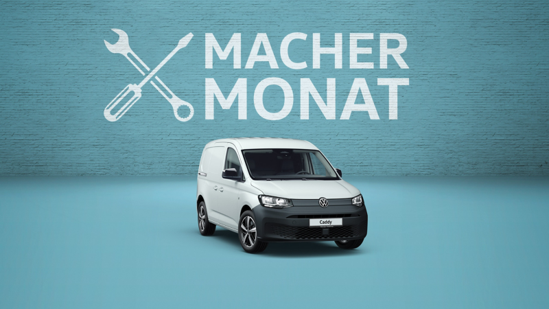 Ein weißer VW Caddy Cargo steht vor einer blauen Backsteinwand mit der großen Aufschrift „MACHER MONAT“ und einem gekreuzten Werkzeug-Symbol.