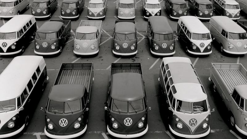 Un parcheggio all'aperto pieno di Volkswagen Bulli con vari allestimenti.
