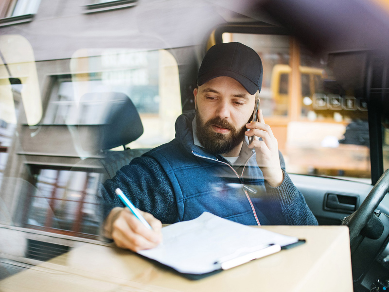 Man talking on the phone and writing on the notepad.