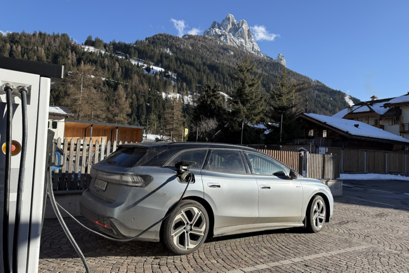 Volkswagen ID.7 vid en laddstation med alperna i bakgrunden.