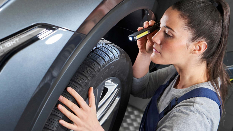 a maintenance expert checking the wheels on an EV VW vehicle