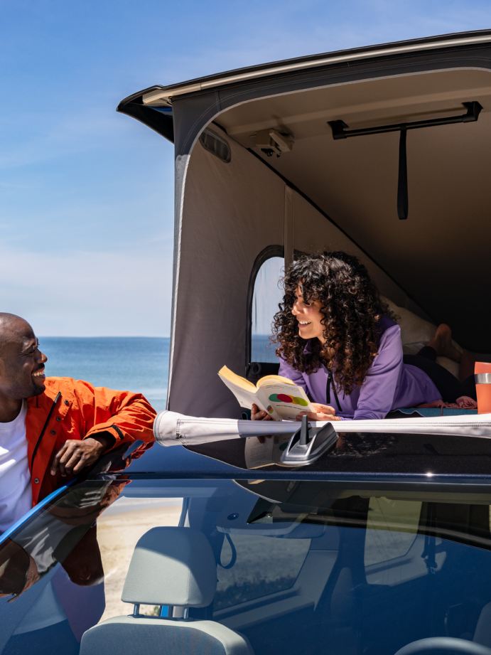 Una mujer y un hombre sentados en la cama del VW California.