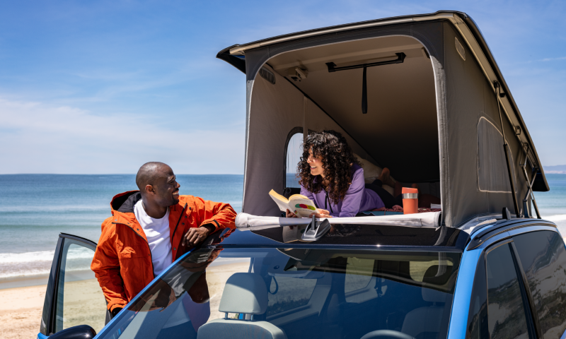 Una mujer y un hombre sentados en la cama del VW California.