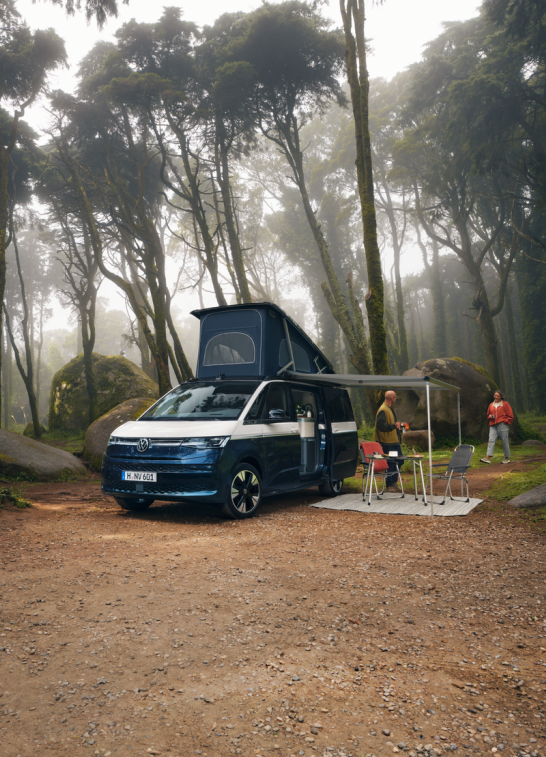 Dos personas junto al VW Nuevo California, con su mesa plegable exterior.