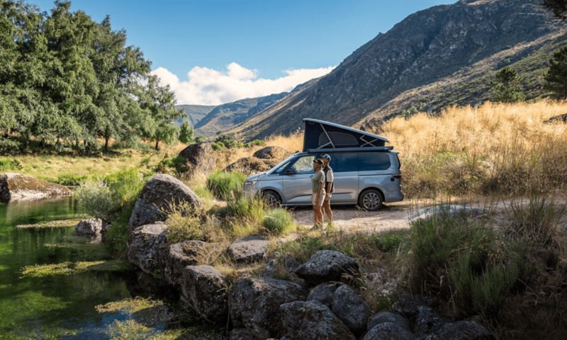 El VW California aparcado en el bosque con el techo elevable.