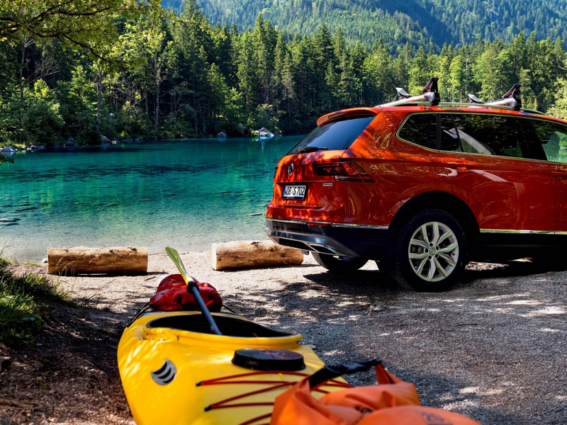 Volkswagen SUV parked by beautiful lake with kayaks at shore