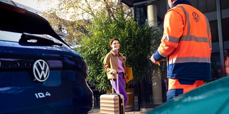 Woman with luggage receiving roadside assistance.