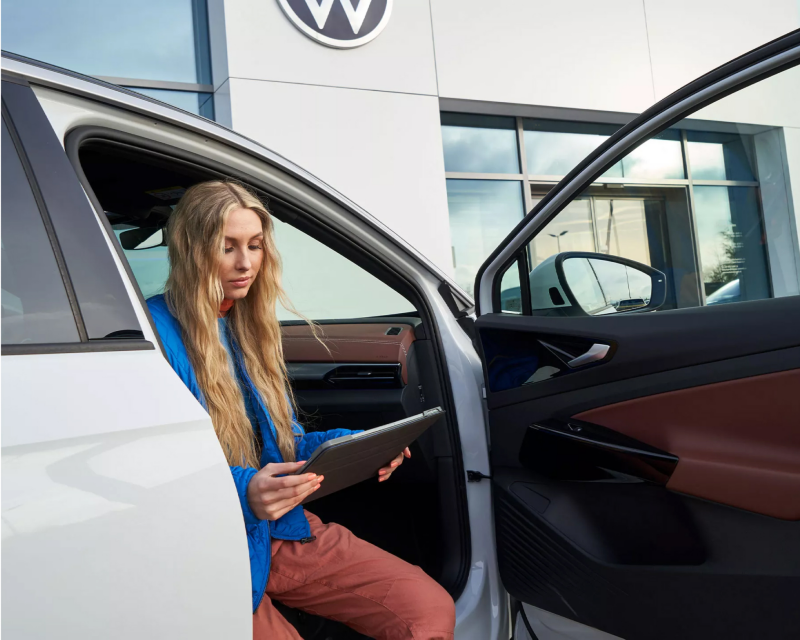 Woman sitting in Volkswagen vehicle using a tablet.