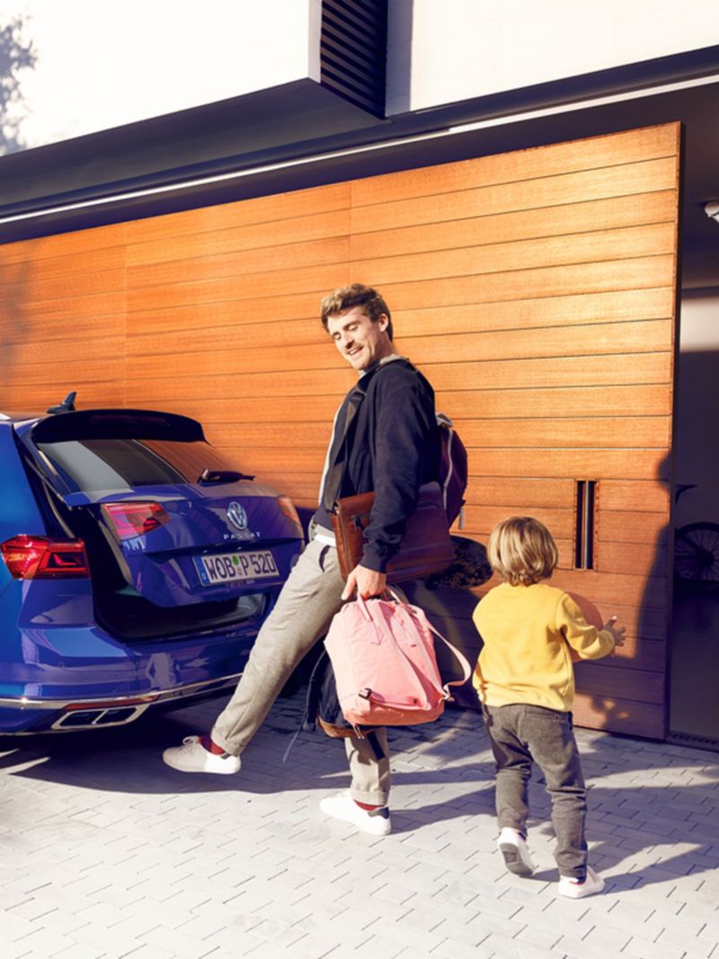 Mann mit Taschen in den Händen öffnet Kofferraum des VW Passat Variant mit dem Fuß per optionaler „Easy Open“-Funktion.