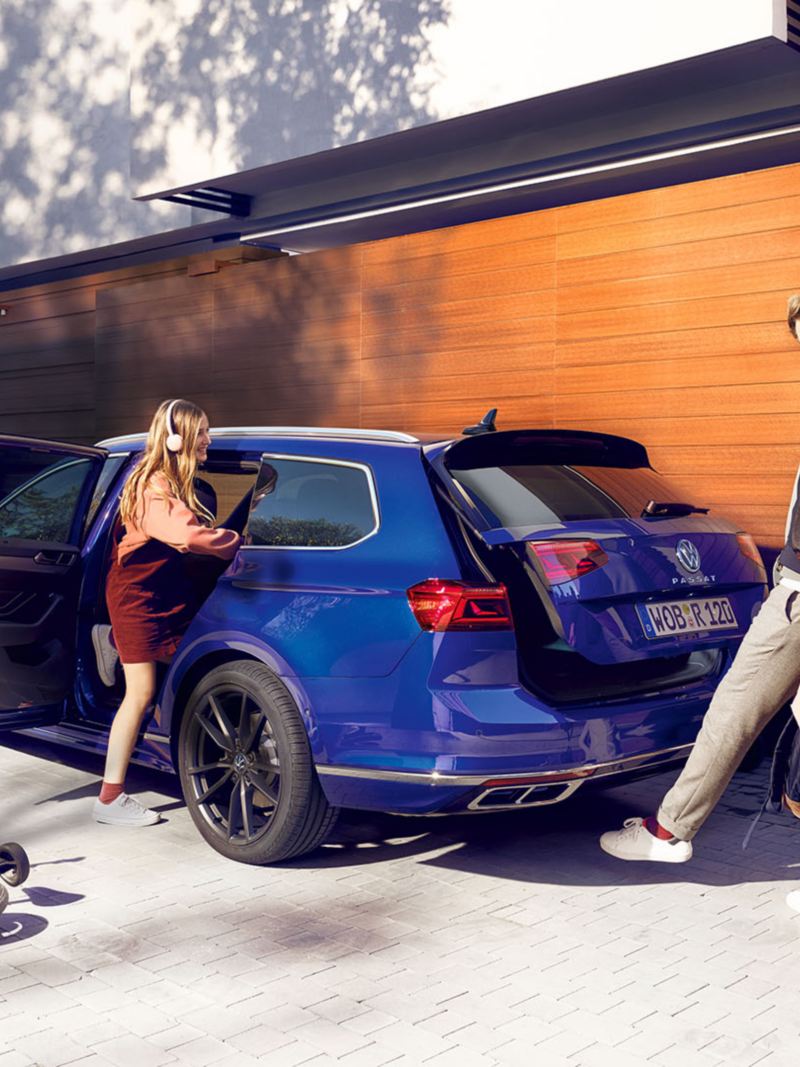 En begagnad Volkswagen Passat Sportscombi parkerad utanför en villa. En man öppnar baklucka med Easy Open-funktionen.