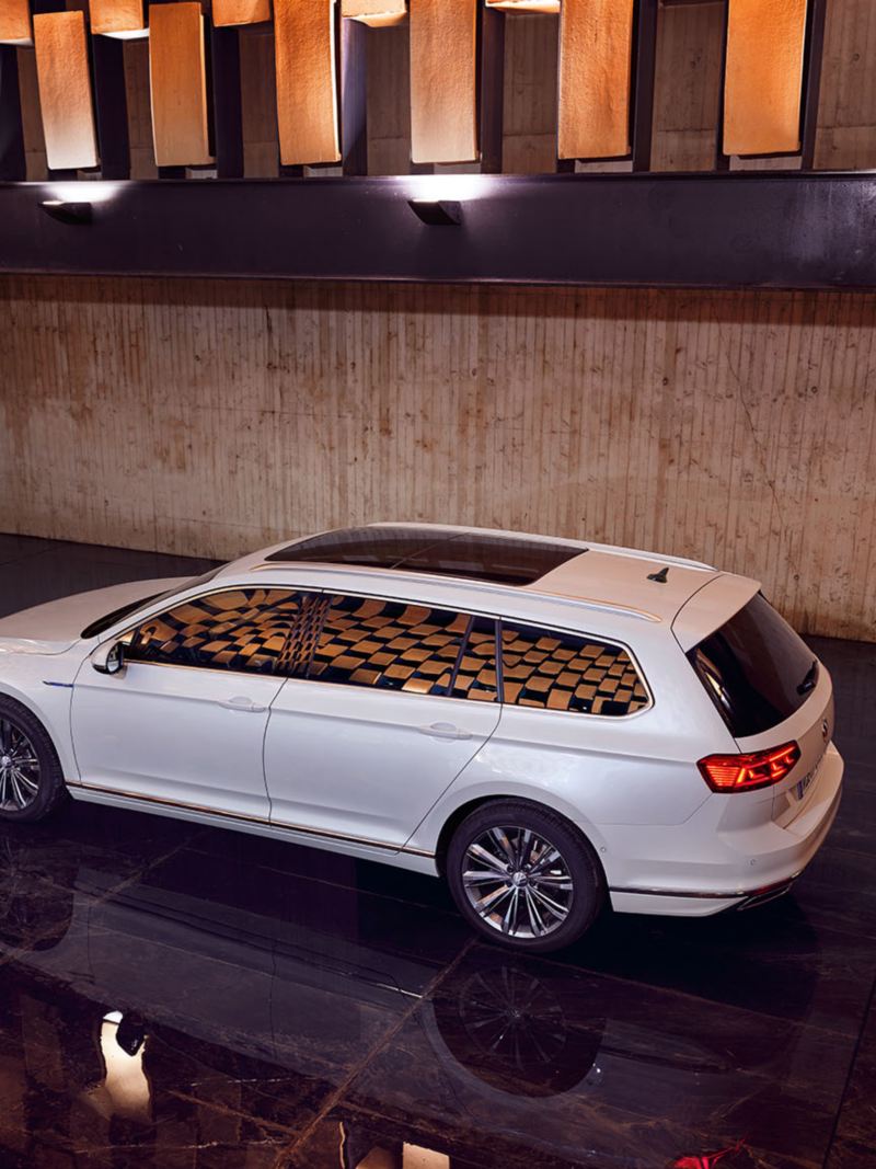 Seitenansicht weißer VW Passat GTE Variant von schräg oben, optionales Panoramadach, eingeschaltete Heckleuchten