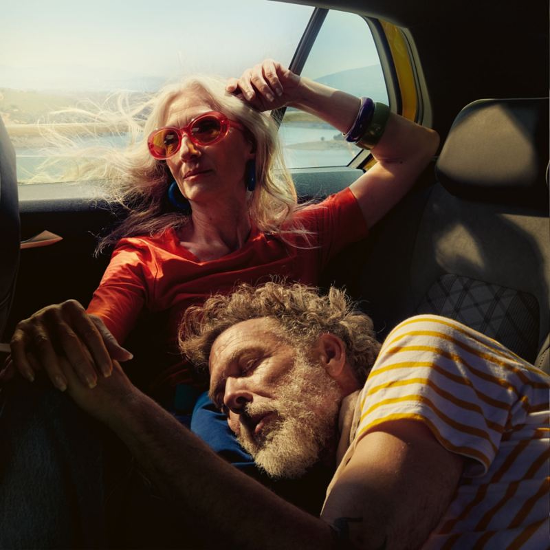 Un couple se trouve sur le siège arrière d’une VW Golf dans la nature.