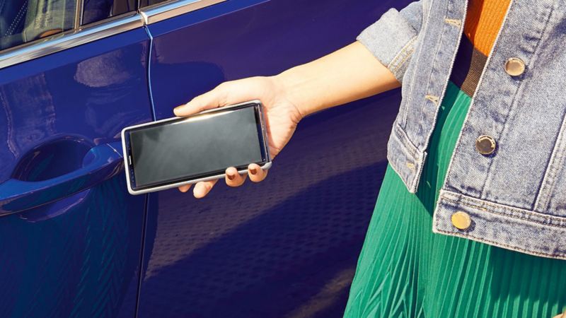 Esterno della Volkswagen Passat, chiave mobile Una donna apre l’auto con lo smartphone