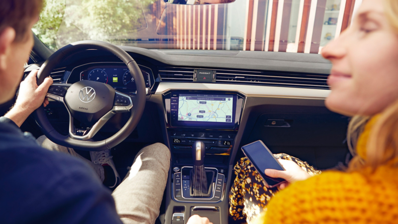 Un uomo e una donna seduti a bordo di una Volkswagen. Il display di bordo mostra il sistema Infotainment.