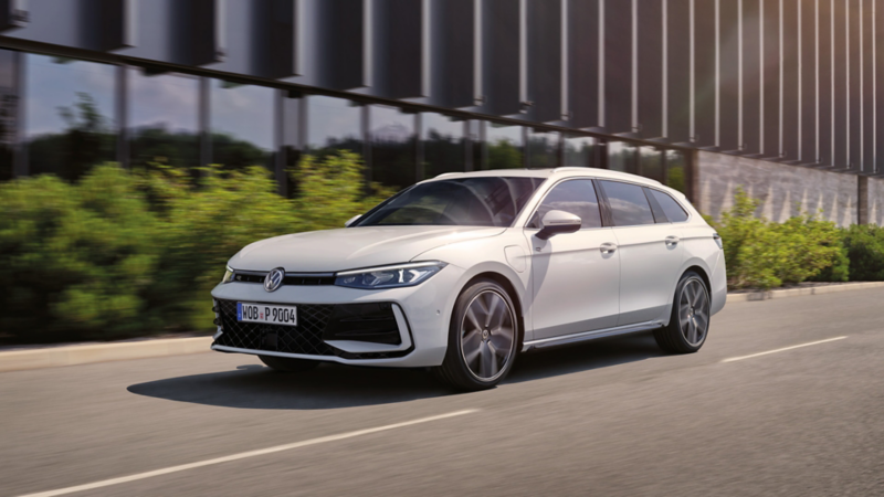 Une VW Passat blanche roule sur une route urbaine.