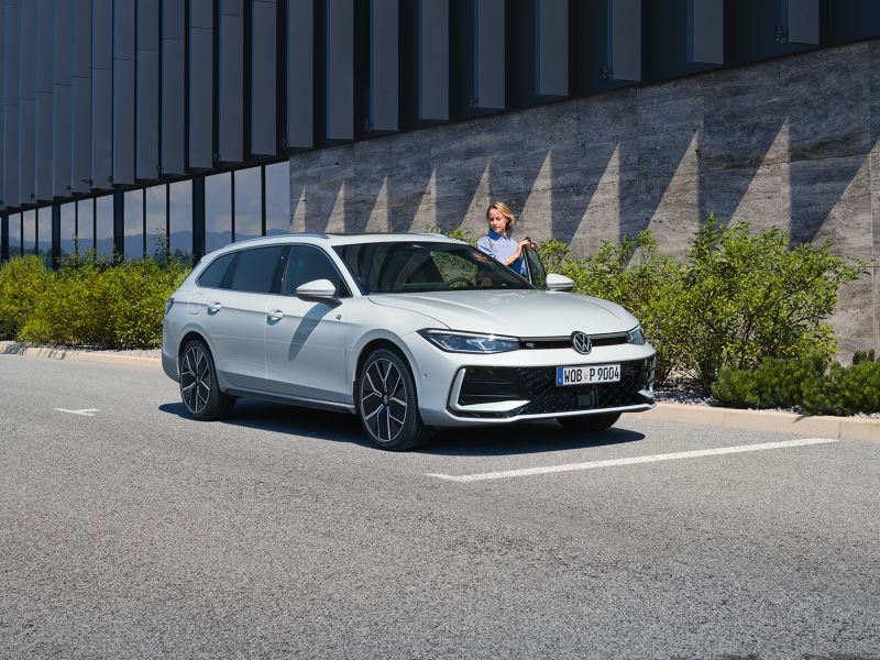 VW Passat blanche garée sur le côté devant un bâtiment.