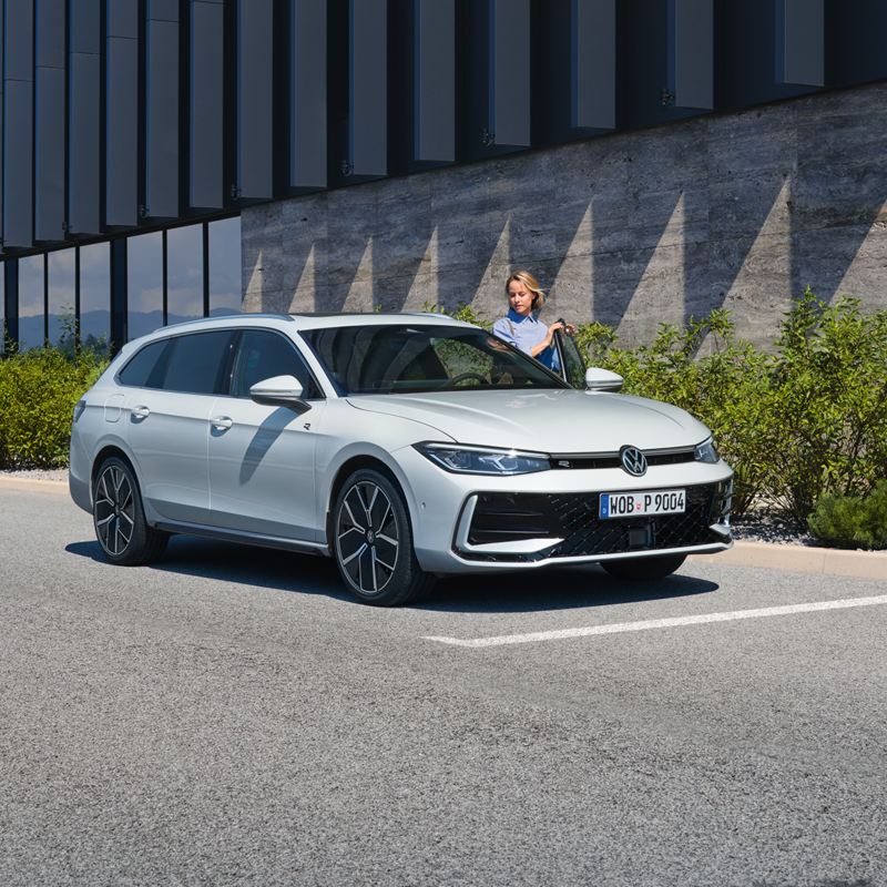 VW Passat blanche garée sur le côté devant un bâtiment.