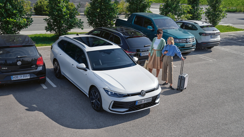 Deux femmes discutent à côté de la VW Passat, vue en plongée, de 3/4 avant.