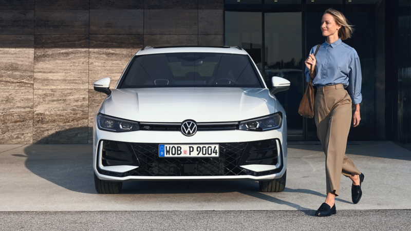 VW Passat eHybrid parkeert voor een gebouw en een vrouw loopt ervoor.